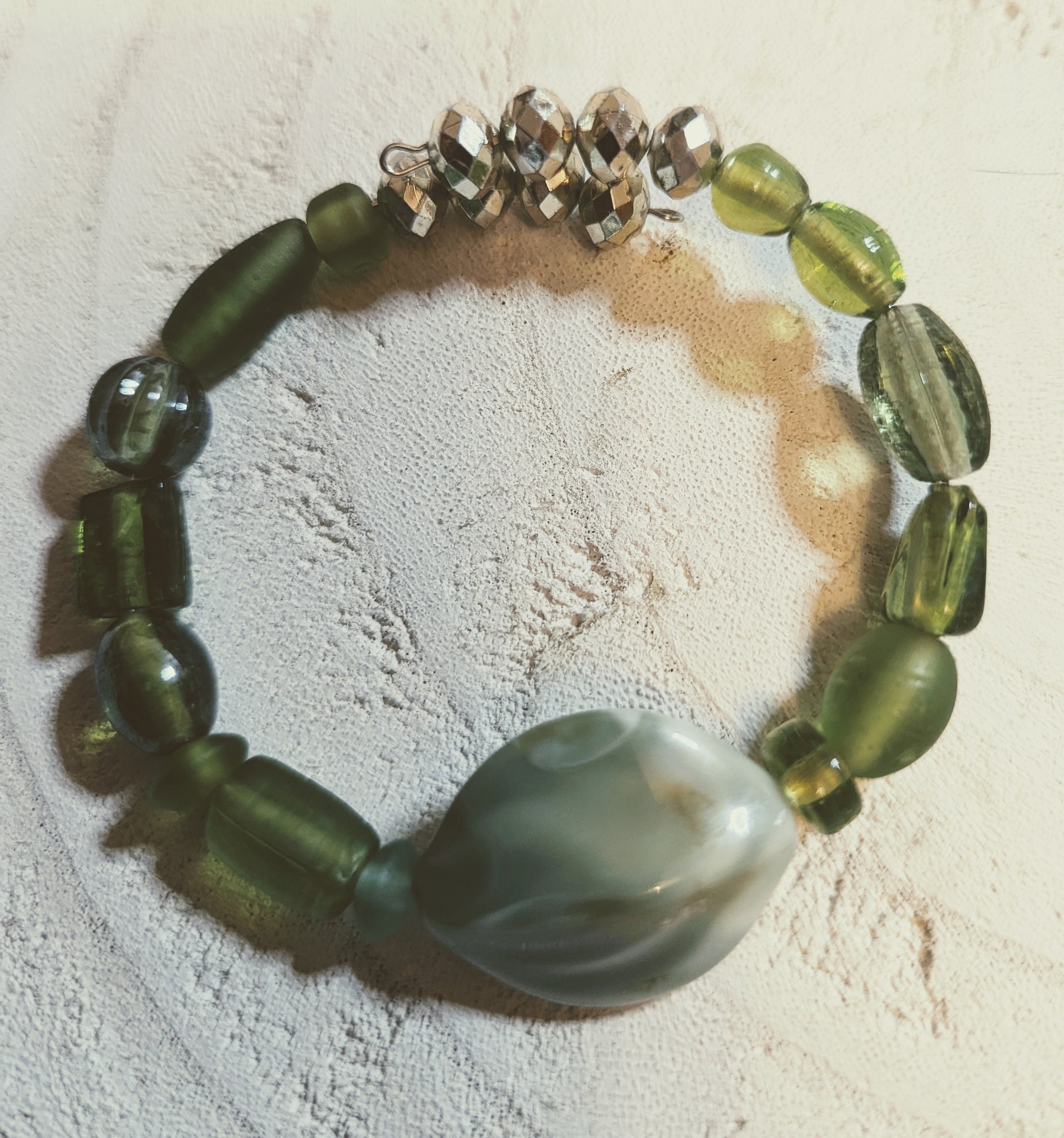 Green beaded bracelet with a large central stone 