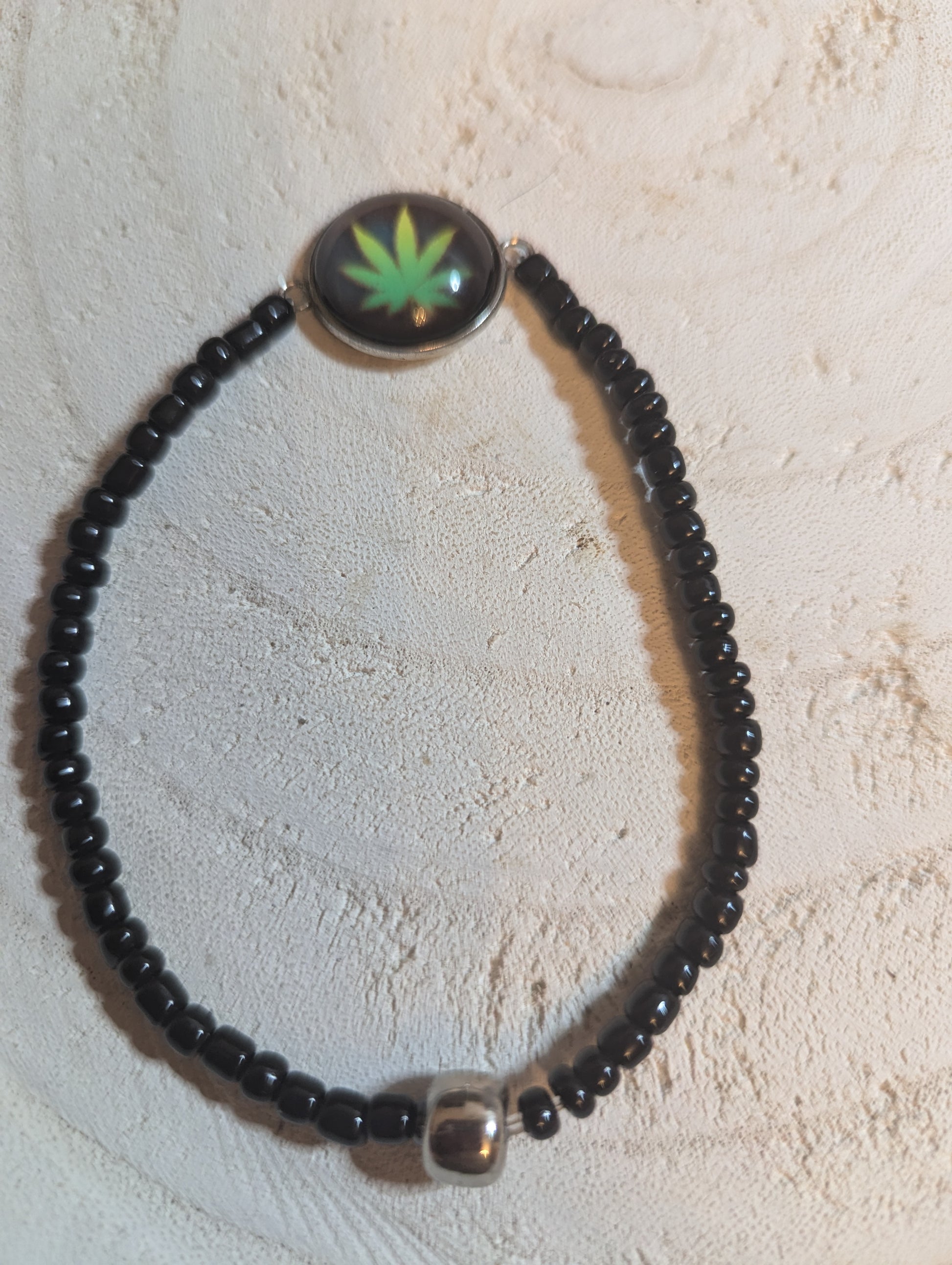 Black beaded bracelet with a green leaf charm 