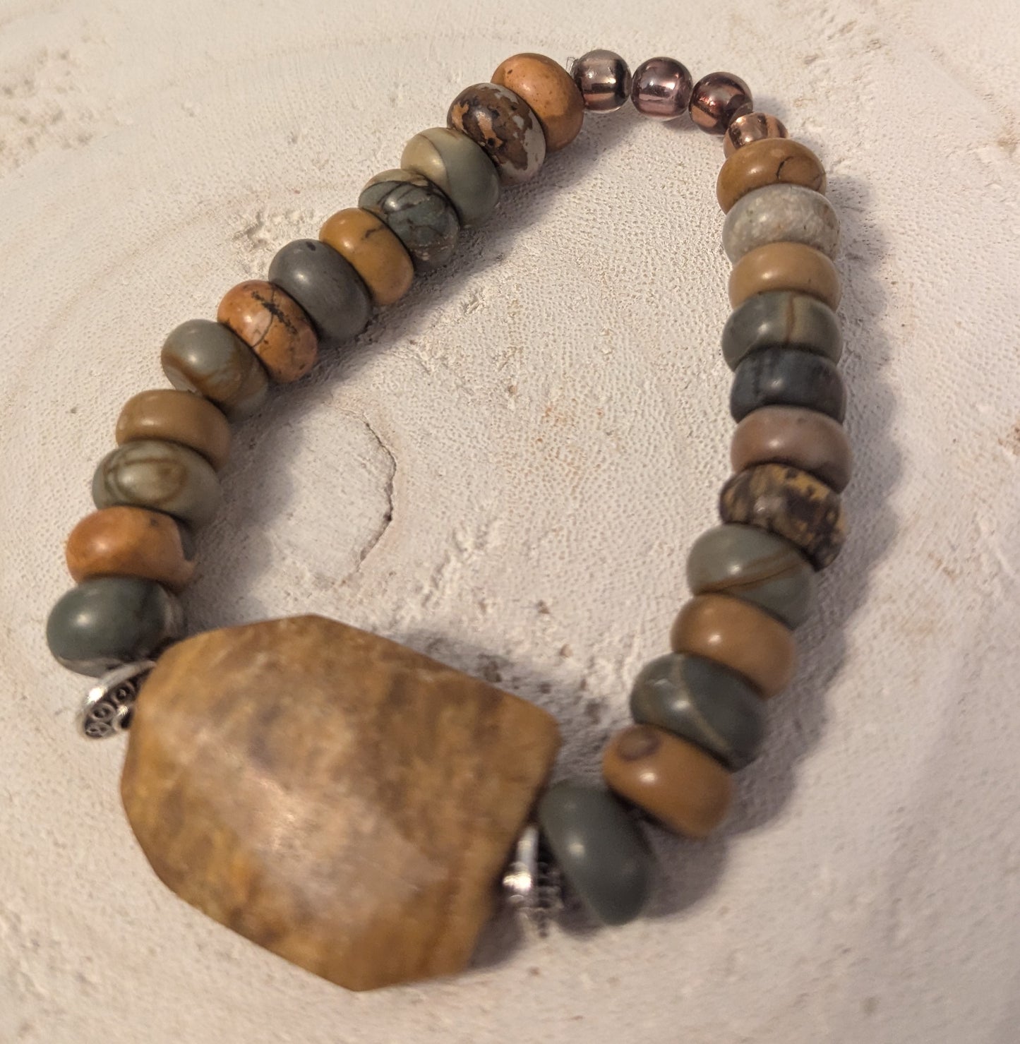 Stones bracelet with a large stone clasp on a textured beige background