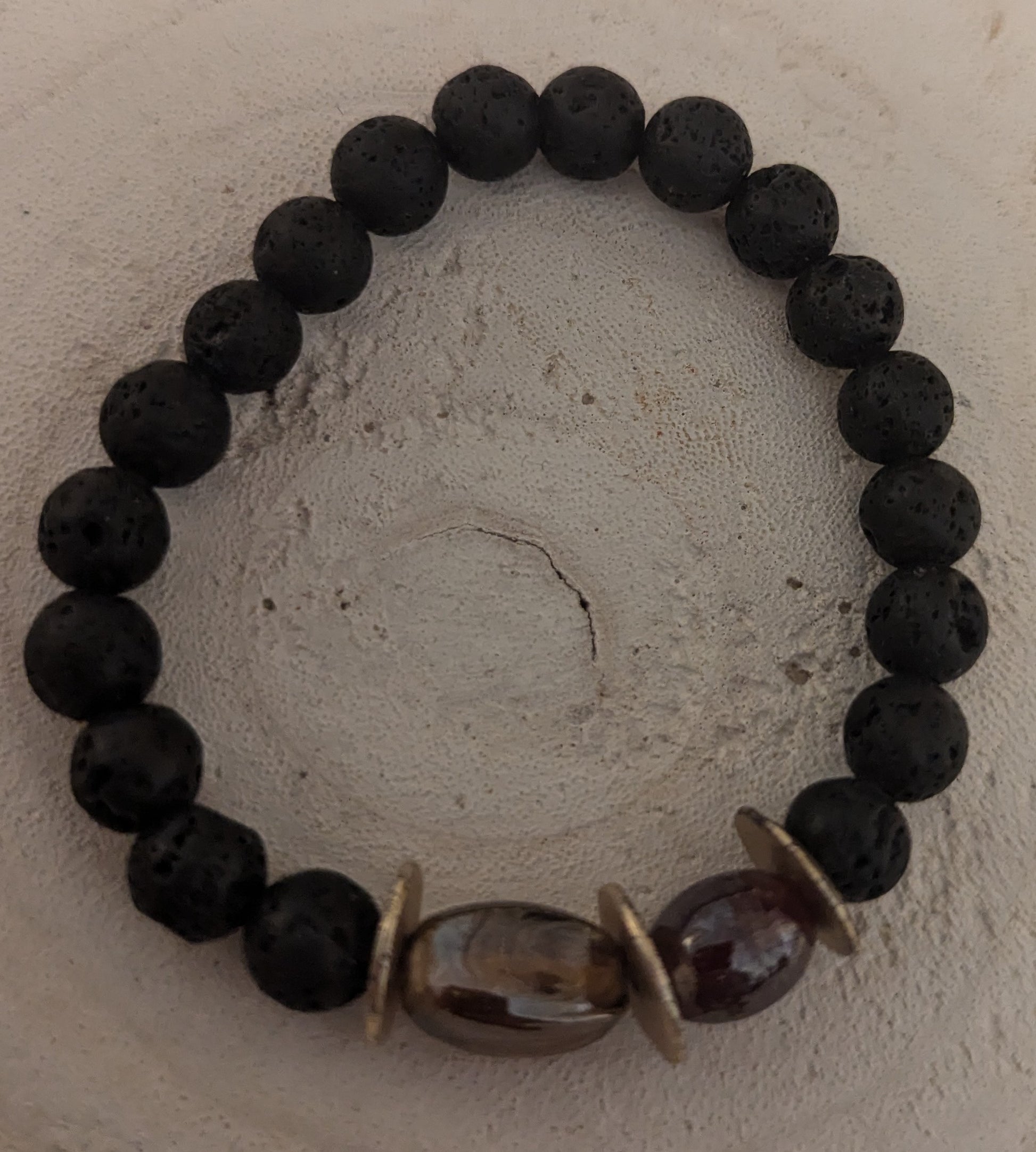 Black lava beaded bracelet with a brown and gold accent bead 