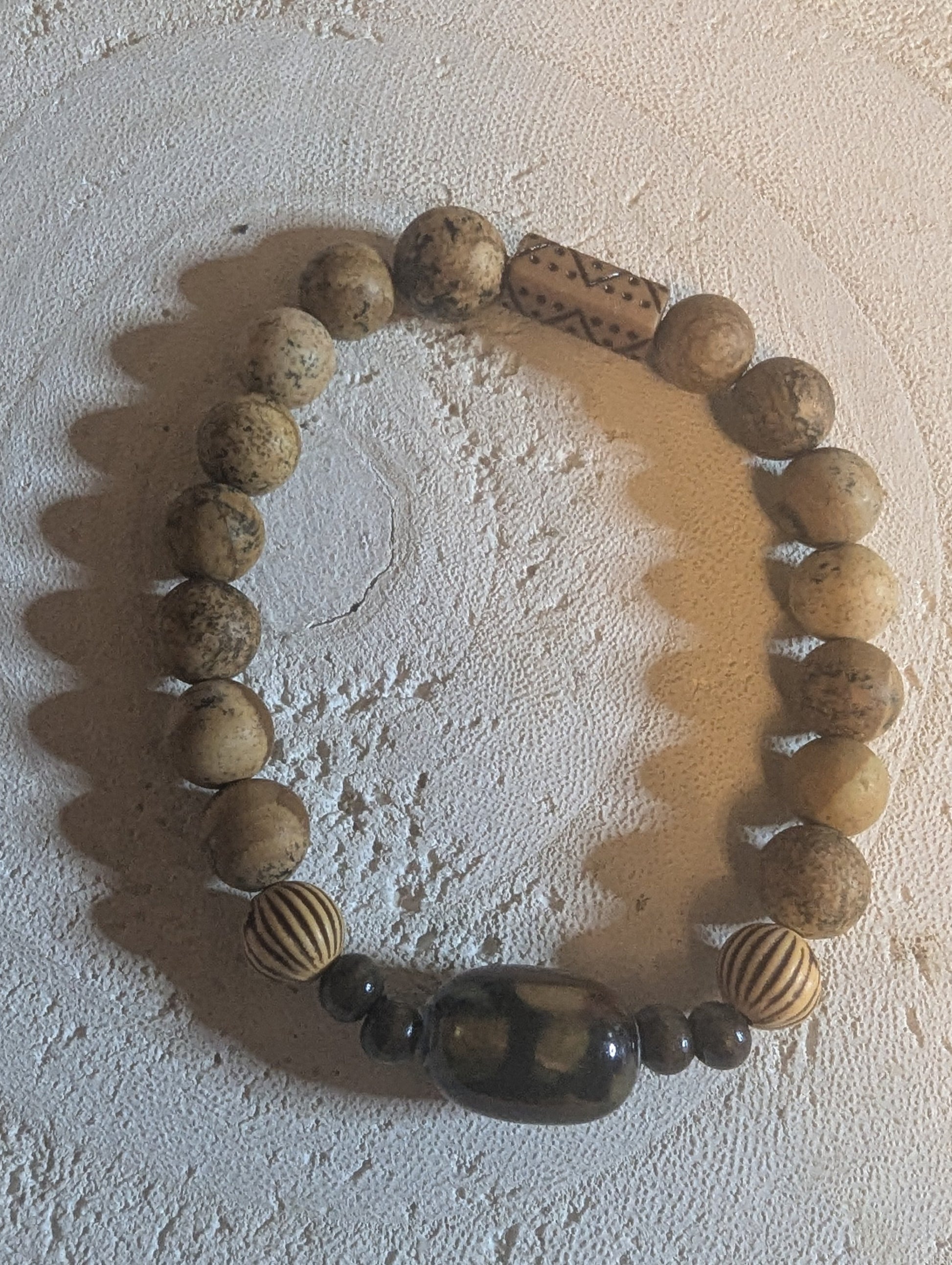 Bracelet made of round wooden beads with ceramic glass pendant.