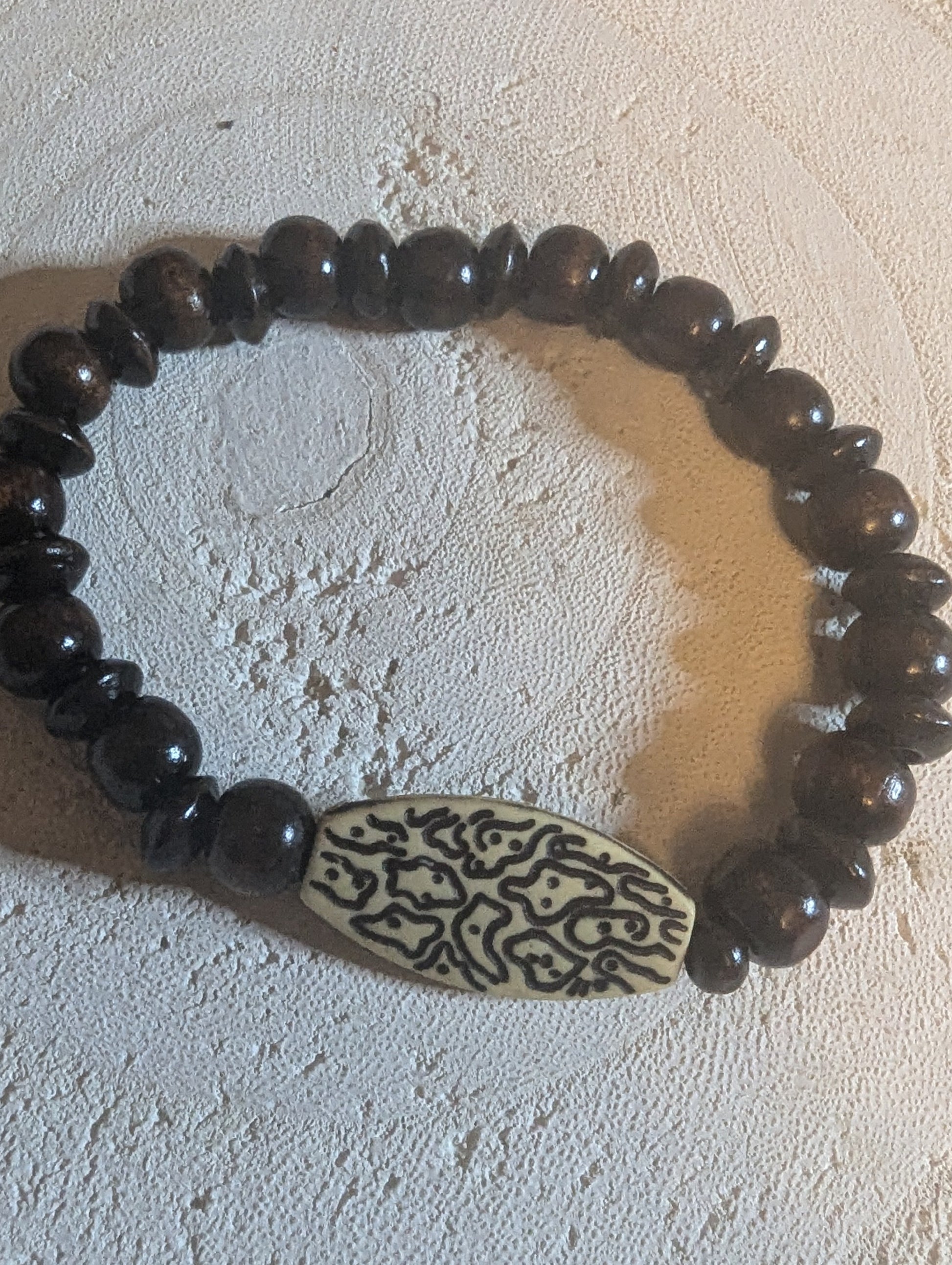 Dark brown beaded bracelet with a decorative pendant
