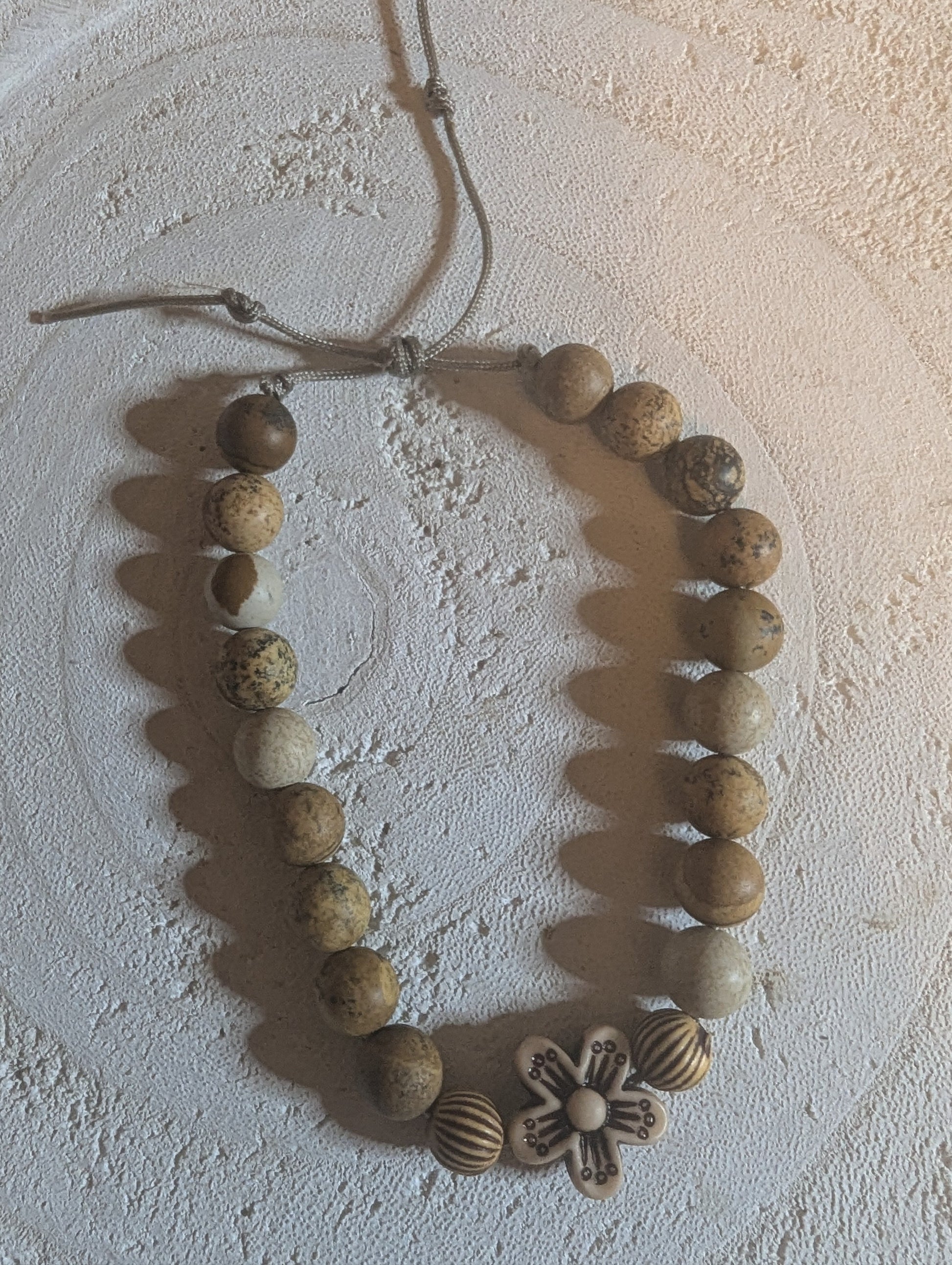 Adjustable bracelet with wooden beads and a flower-shaped charm