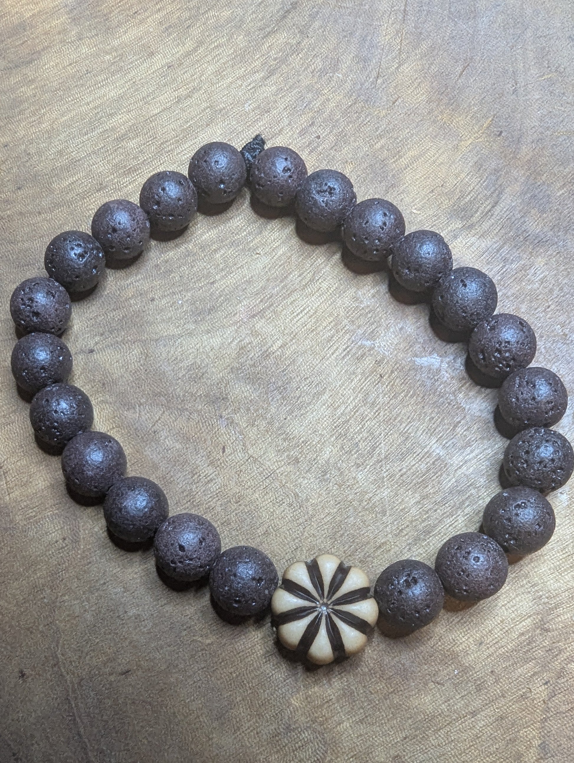 Brown beaded bracelet with a distinctive floral bead 