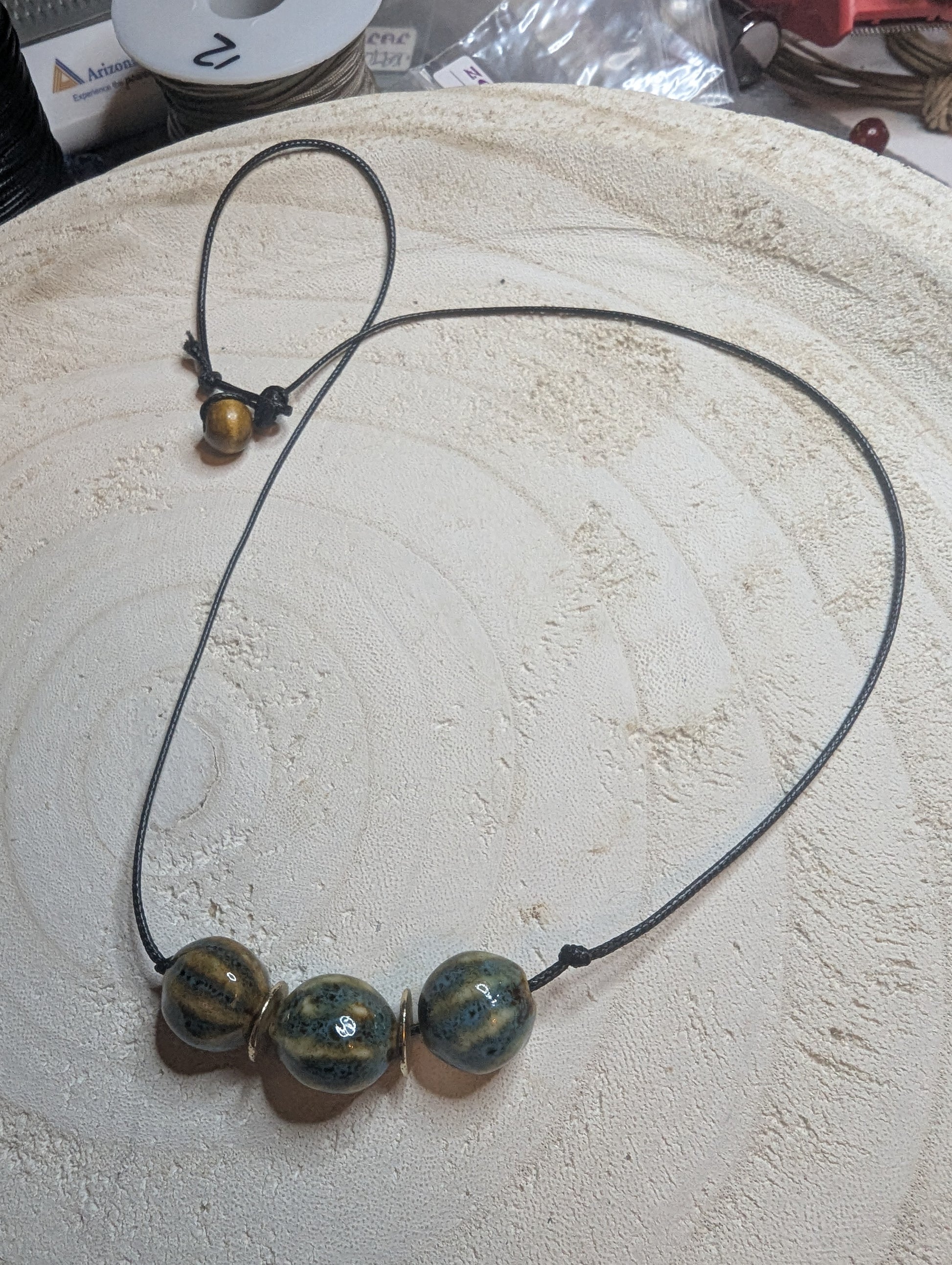 Necklace with three blue-tan beads on a leather cord.