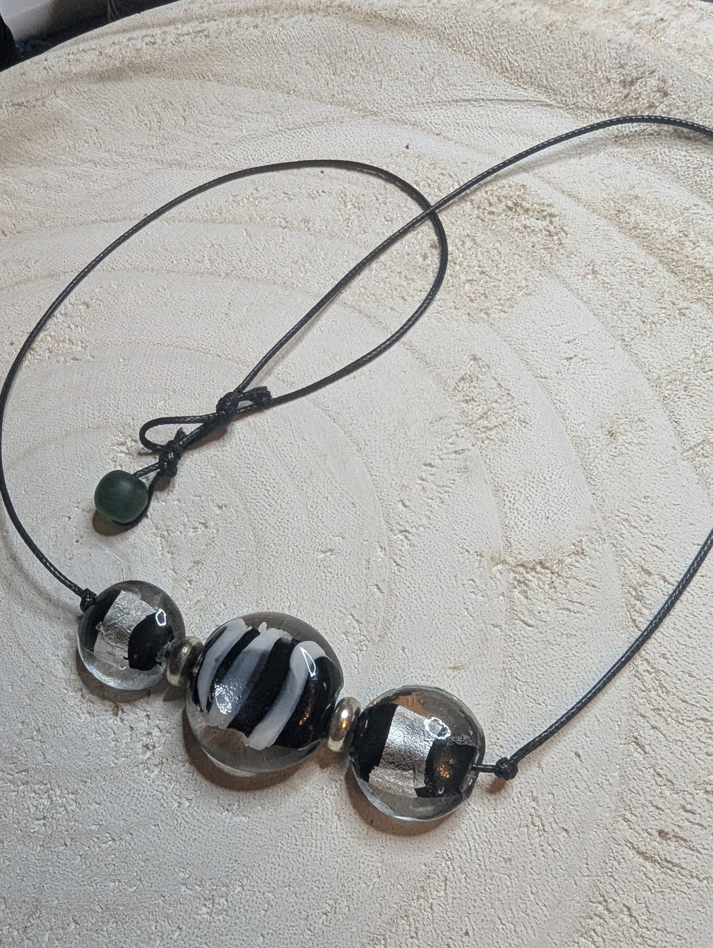 Necklace with black and white beads on a leather cord.