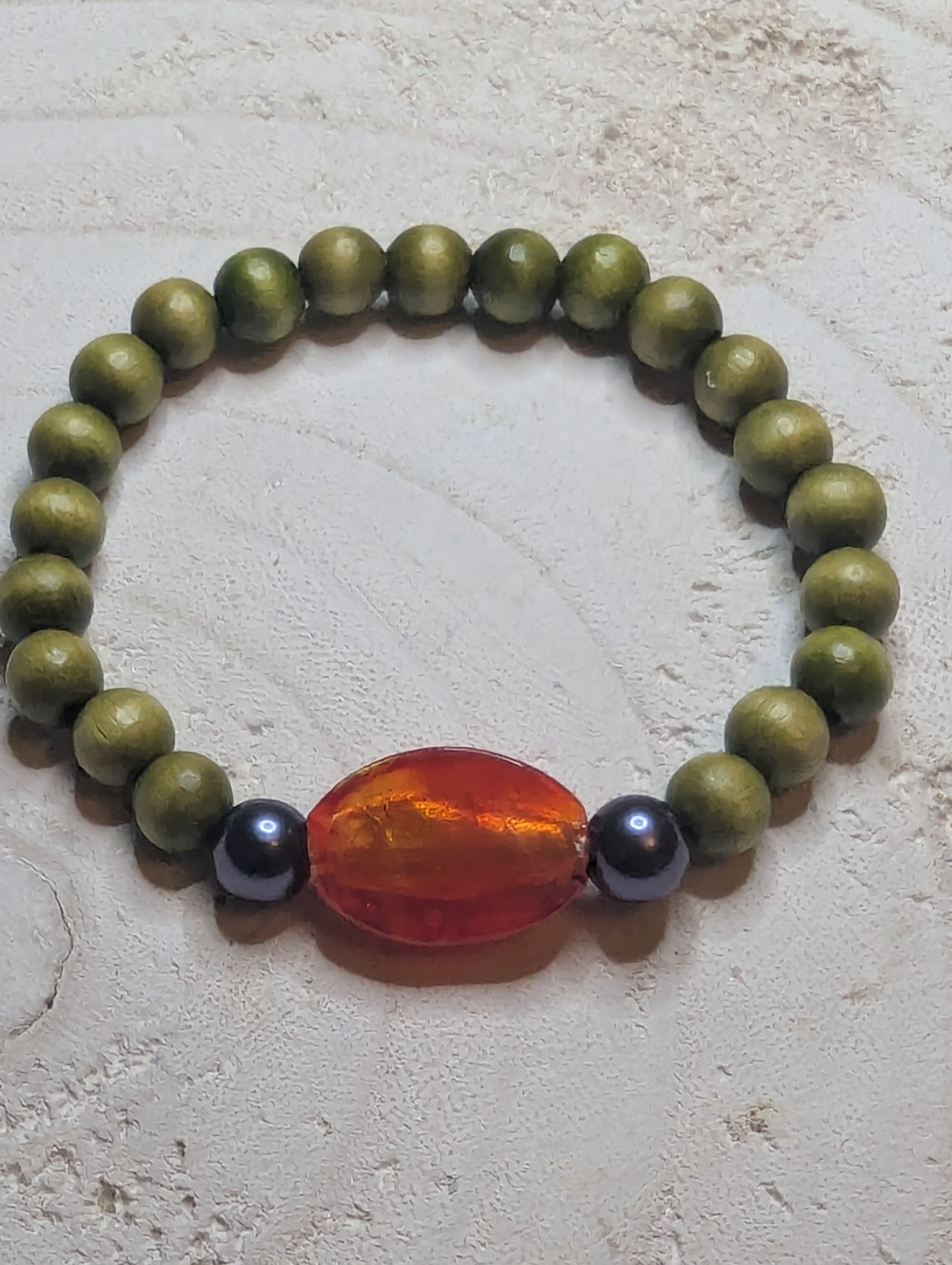 Green beaded bracelet with an orange and black bead 