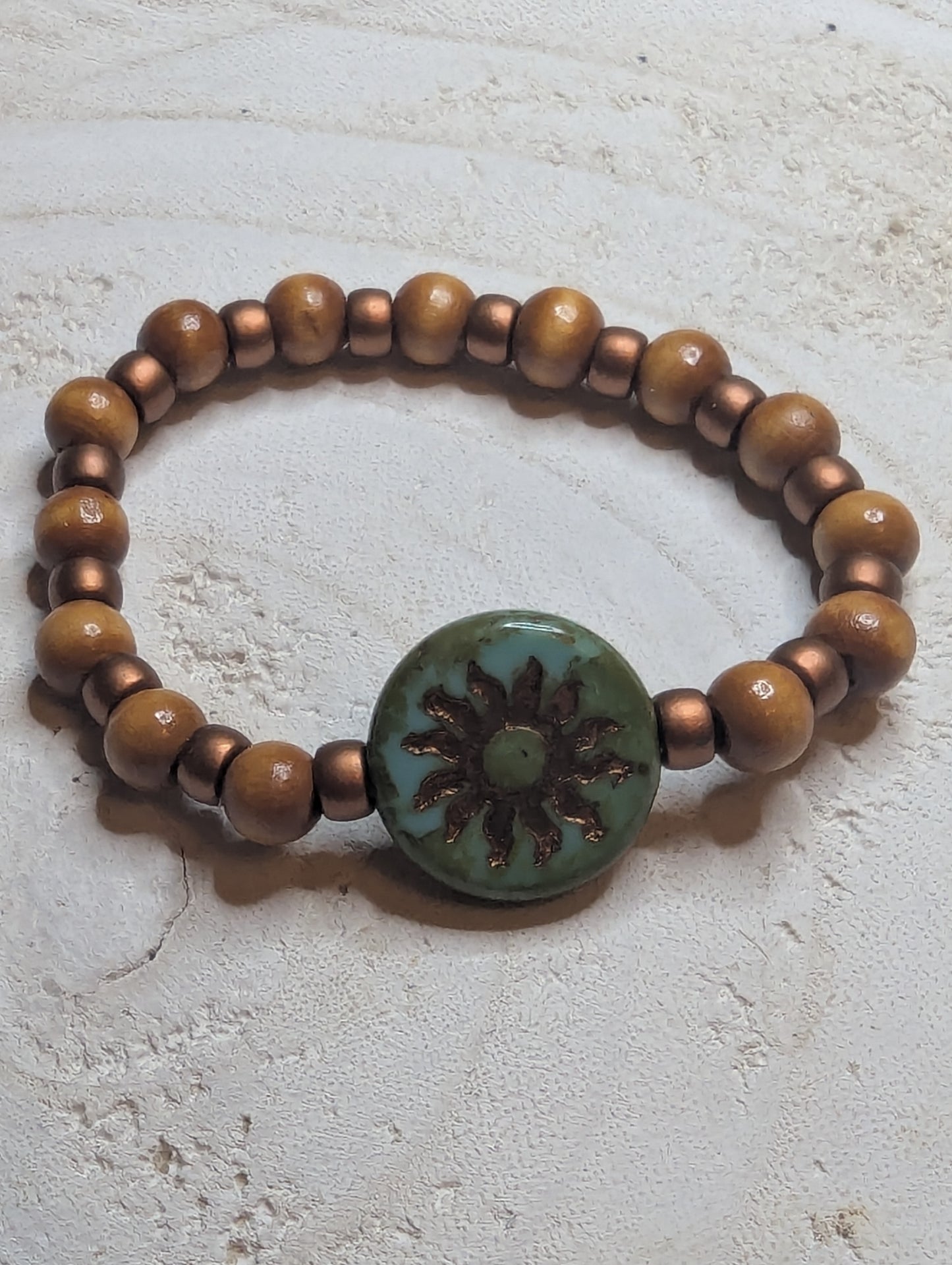 Bracelet with brown beads and a green button featuring a  sun design 
