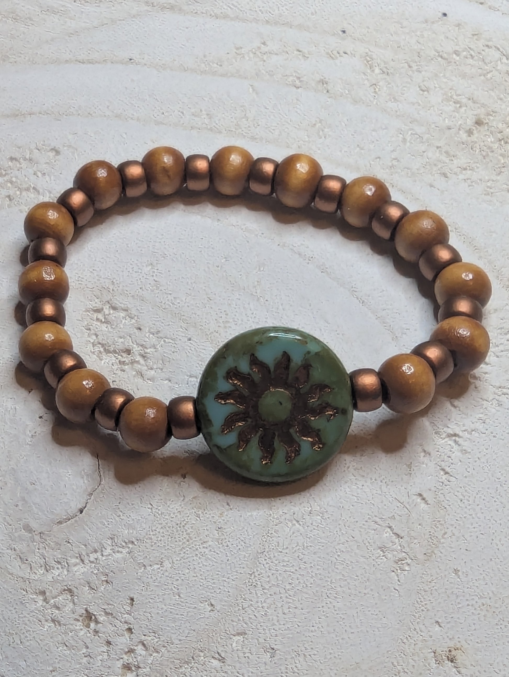 Bracelet with brown beads and a green button featuring a  sun design 