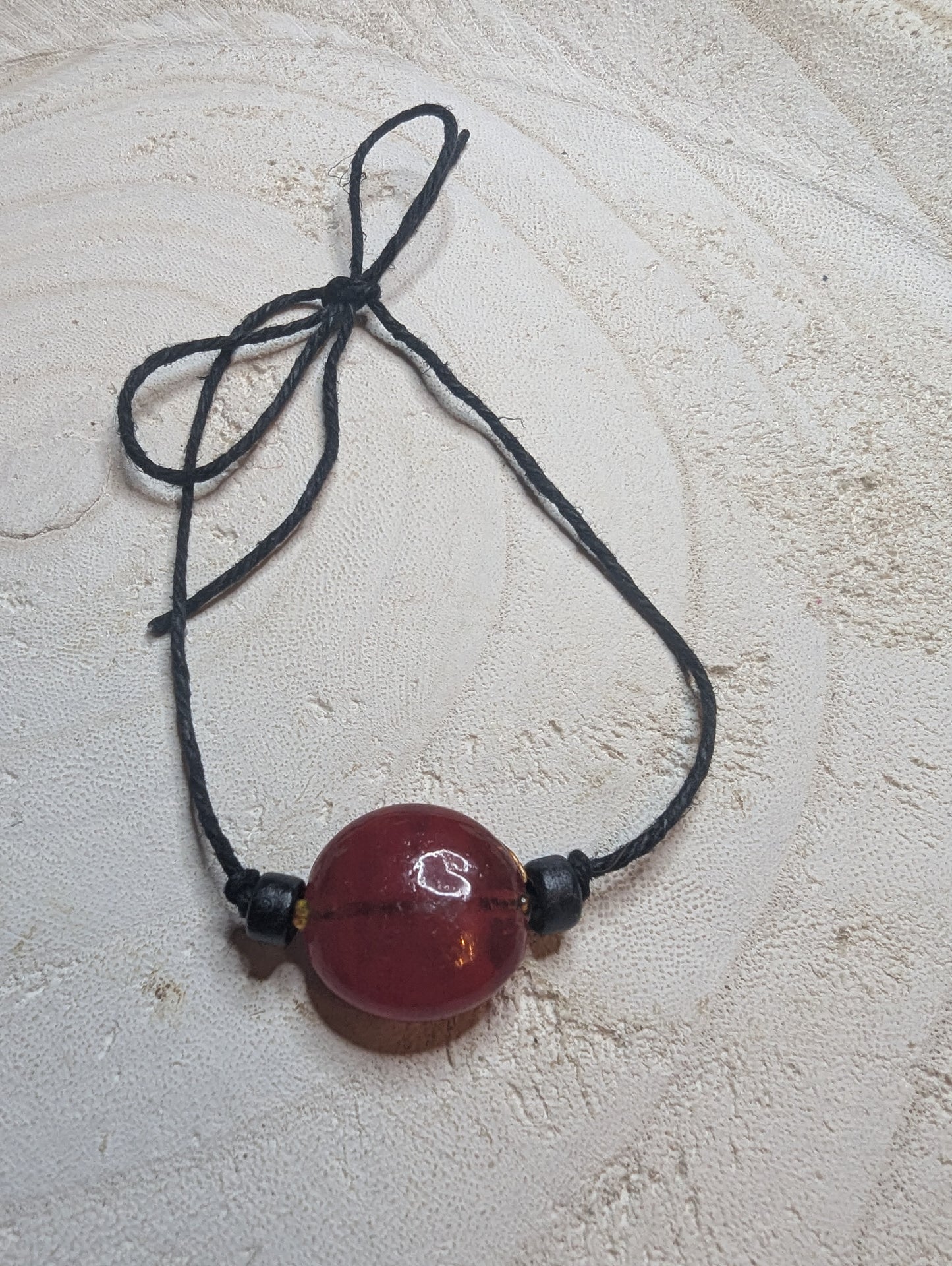 Adjustable bracelet with a reddish ornage bead 