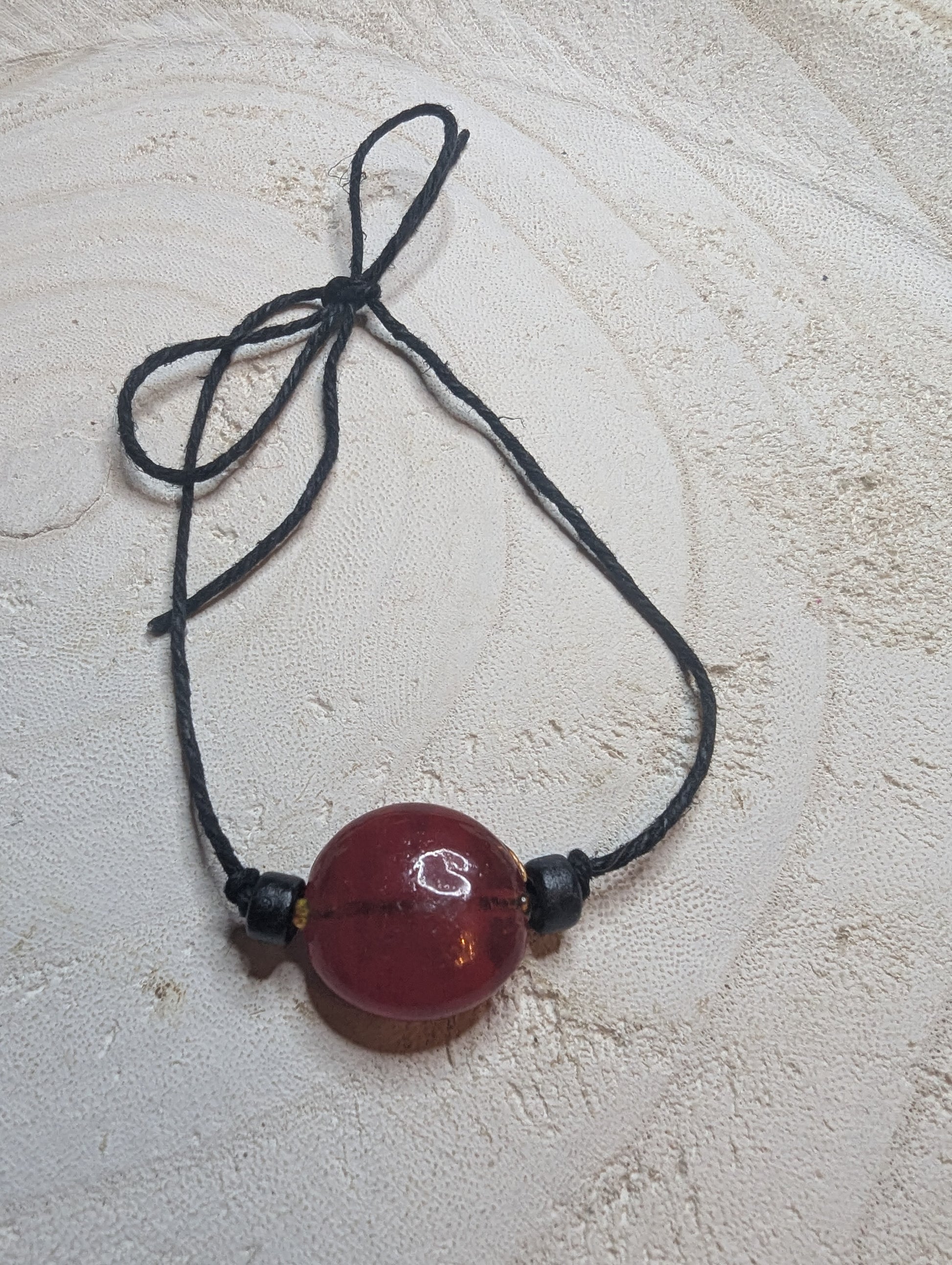 Adjustable bracelet with a reddish ornage bead 