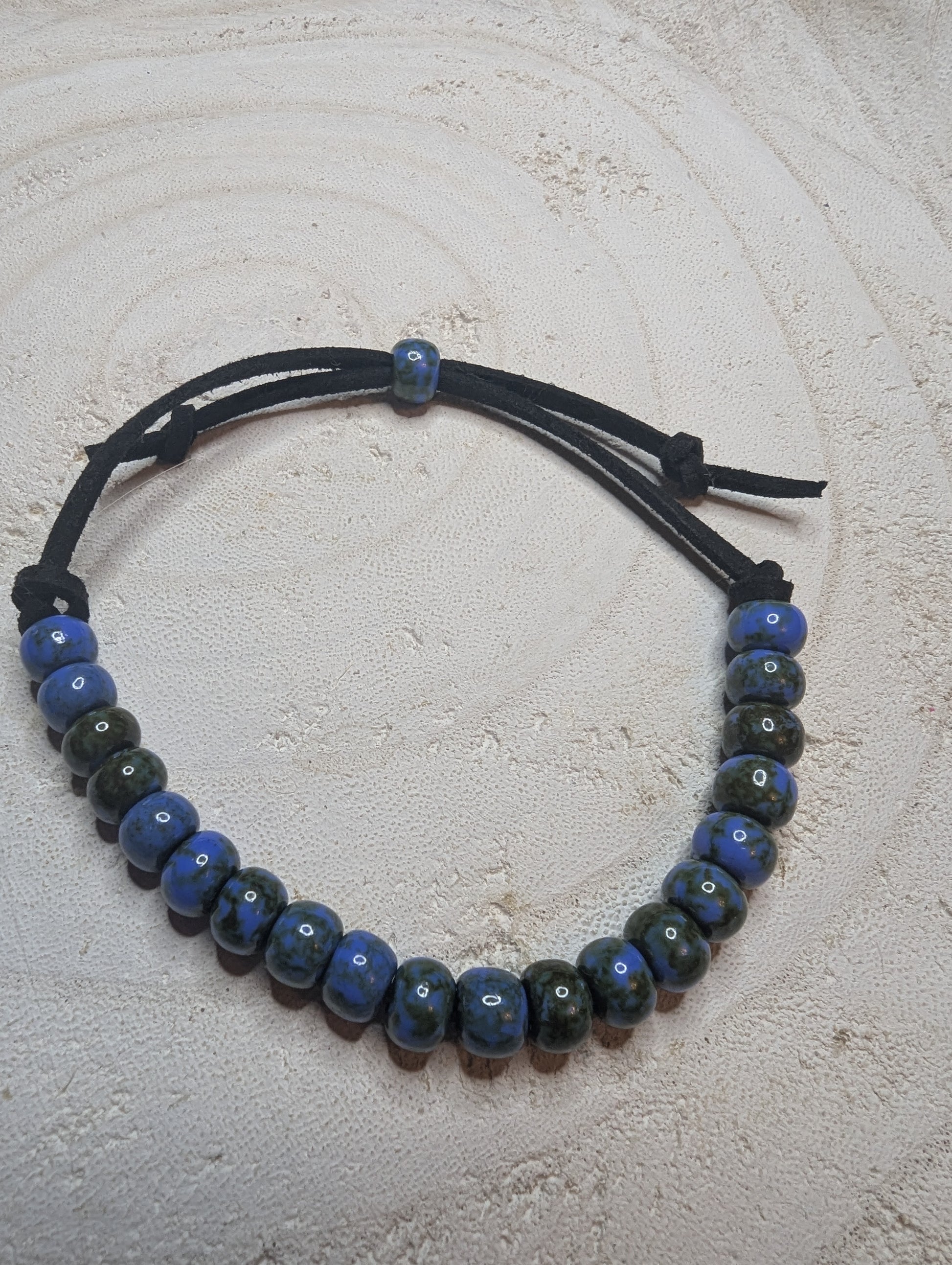  Beaded bracelet with blue and black beads on a black leather adjustable strap