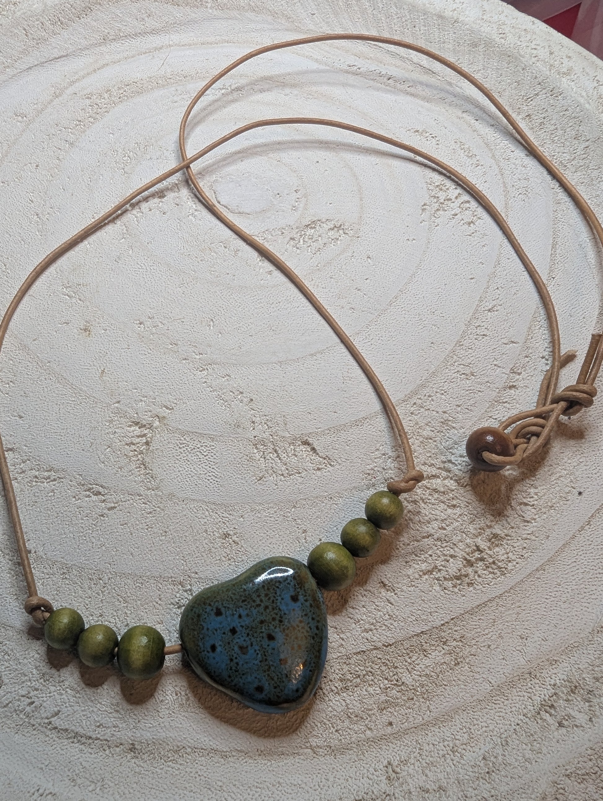 Necklace with a heart-shaped green wooden stone and a blue-brown stone pendant on a beige cord  from Sedona, AZ